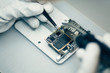 © Javier Pardina/Stocksy - Man repairing smartphone.