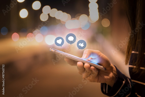 Fotografie, Obraz Woman hands using mobile smartphone in the street with icon social media and social network