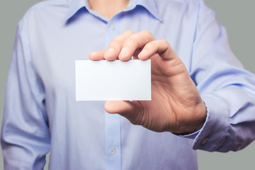 The men in the shirt are holding an empty white business card in their hands. Mockup, template