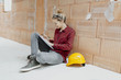 © epiximages - young, pretty, blonde woman with yellow helmet is planning on the notebook and tablet the expansion of her loft