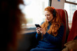 © Connect Images - Woman on train listening to music on mobile phone with headphones, London