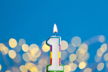 Number 1 Birthday Celebration Candle Against A Bright Lights And Blue Background