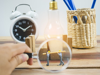 Miniature people engineer worker on wood table and white background . Around have a magnifying glass, clock and quare wood.