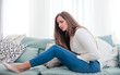 © leszekglasner - Woman suffering from abdominal pain while sitting on sofa at home