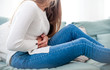 © leszekglasner - Woman suffering from abdominal pain while sitting on sofa at home