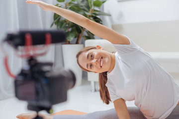 Feeling happy. Emotional young health blogger feeling happy while bending and smiling to the camera