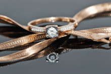 Gold Diamond Ring Rests On A Chain With A Snake Weaving