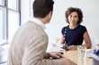 © Cavan Images - Smiling businesswoman talking with colleague in meeting at office