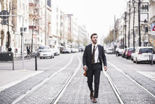 Full Length Of Businessman Walking By Railroad Tracks In City