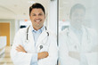 © Cavan Images - Portrait of smiling doctor with arms crossed standing in hospital