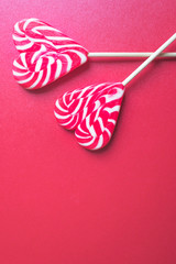 Close up and tow view of red and white striped lollipops isolated on red background with copy space. Love, romance or Happy Valentine's day concept