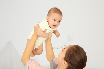 Poster - Portrait of young mother playing with cute baby at home