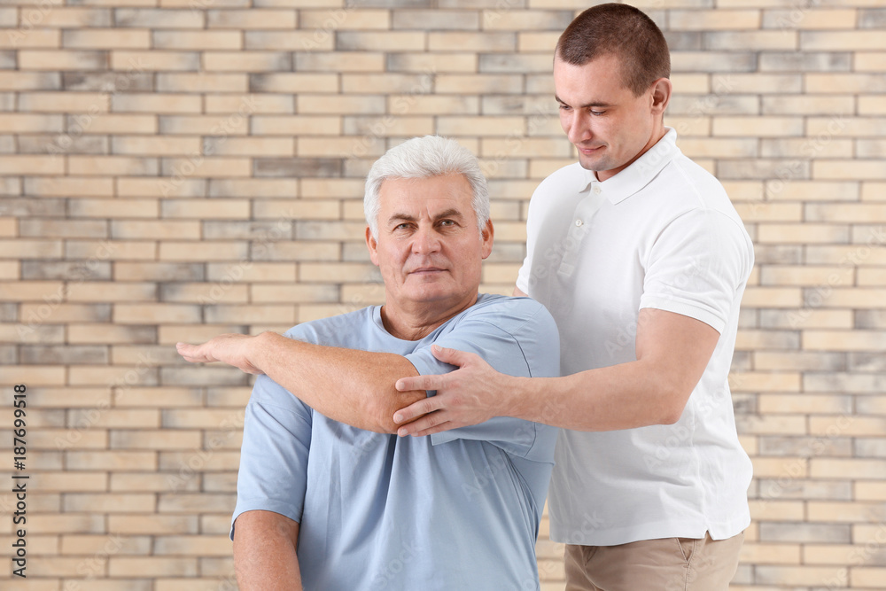 Physiotherapist working with patient on brick wall background
