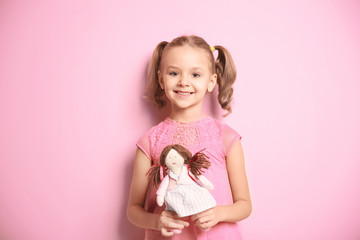 cute little girl with doll on color background