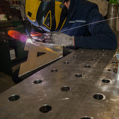 man in concentrate on welding tig mode an aluminium letter