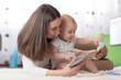 © Oksana Kuzmina - Mother showing images in a book to her cute baby son at home