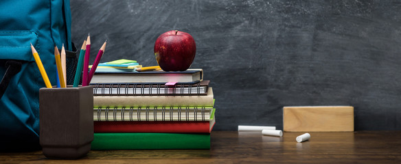 Stack of books, colorful stationery and education supplies on wooden table