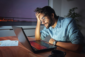 Wall Mural - Businessman working on a laptop, overworking, under pressure, tired and sleepy  