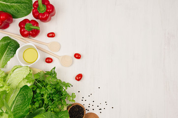 Wall Mural - Cooking fresh spring salad of green and red vegetables, spices on white wooden background, border, top view.