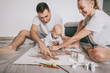© LIGHTFIELD STUDIOS - happy young family with cute little child painting together on floor at home