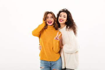 Wall Mural - Two smiling girls in sweaters posing together