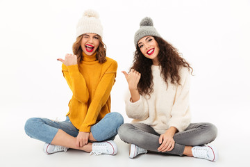 Poster - Two playful girls in sweaters and hats sitting on floor