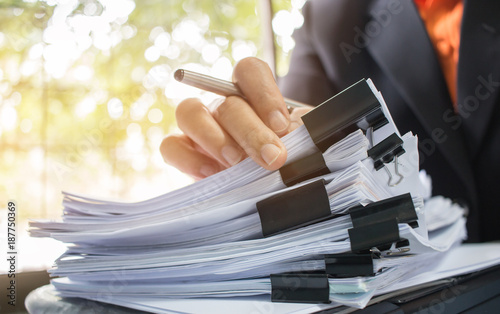 Cuadros en Lienzo Businessman hands working in Stacks of paper files for searching information on