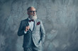 © deagreez - Portrait of proud respected confident handsome masculine virile vintage grey-haired sharp dressed in bespoke checkered grey suit with vinous handkerchief brutal macho isolated on concrete background