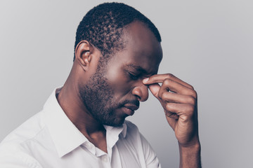 Side profile close up view portrait of nervous stressed depressed unsatisfied hard-working african man with closed eyes touching nose-bridgt trying to concentrate isolated on gray background