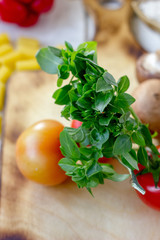 Sticker - Green basil leaves on kitchen board with vegetables.