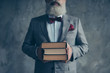 © deagreez - Cropped close up photo of smart serious confident modern stylish trendy teacher dressed in checkered grey jacket with vinous bow-tie handkerchief showing a pile on book isolated on grey background