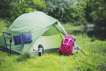 Wall Mural - Camping on the river bank. The solar panel hangs on the tent.