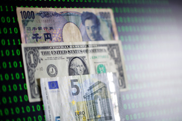 japanese yen,us dollar and euro notebank among binary code background with copyspace