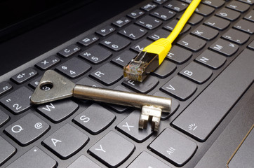 Silver colored key and network communication plug lying on computer keyboard