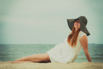 Redhead woman wearing sun hat lying on beach