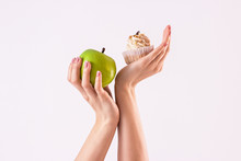 Try To Choose. Studio Shot Of Woman Deciding Between Healthy And Unhealthy Food. Woman Holding Green Apple In One Hand And Cake In Other, Isolated On White Background. Healthy Lifestyle Concept