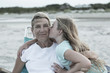 © Marc Romanelli/Blend Images - Girl kissing mother on cheek at windy beach