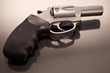 A 44spl stainless steel revolver with a black handle laying upon a glass surface