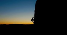 Aerial - Silhouette Of A Man Rock Climbing In The Evening Light.
