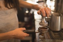 Barista Using A Tamper To Press Ground Coffee Into A Portafilter