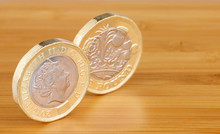Two New English One Pound Coins On A Wooden Background