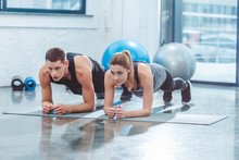 Sporty Young Couple Doing Plank Exercise In Gym