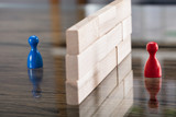 Fototapeta  - Red And Blue Figurine Paw Separated By Wooden Blocks