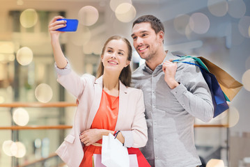 Wall Mural - happy couple with smartphone taking selfie in mall