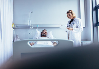 Doctor writing on clipboard while interacting with patient