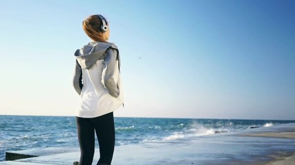 Poster - Back view of Beauty brunette sports woman in headphones walking at the seaside