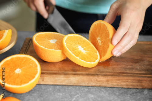 Fotografía Woman cutting orange on board in kitchen
