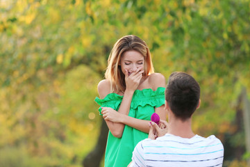 Wall Mural - Young man with engagement ring making proposal of marriage to his girlfriend in park