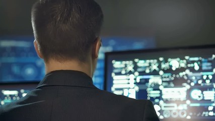 Back view of programmer working on computer in dark digital office