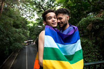 Gay Couple Embracing with Rainbow Flag in the Park